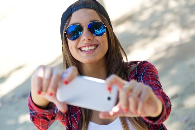 휴대 전화와 함께 selfie를 복용하는 아름 다운 여자의 초상화