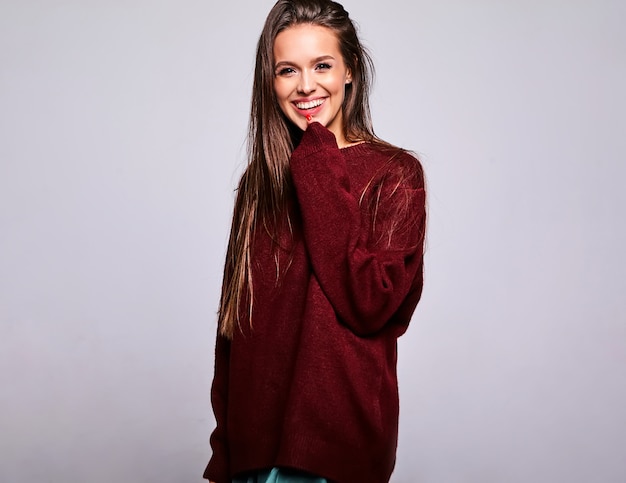 Portrait of beautiful happy cute brunette woman model in casual warm red sweater clothes isolated on gray with evening makeup and colorful lips