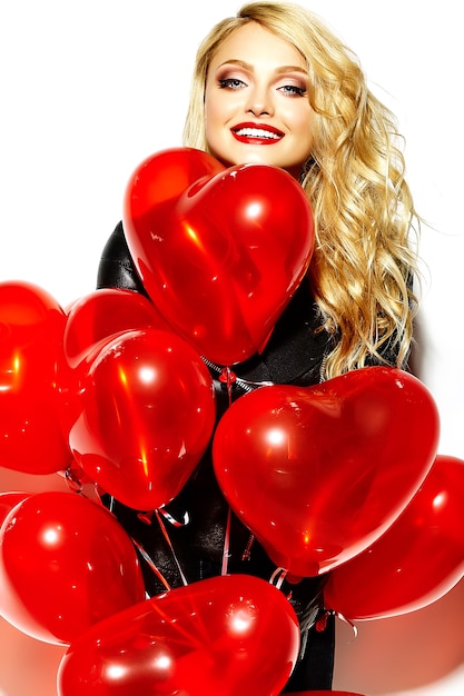 portrait of beautiful happy sweet smiling blonde woman girl holding in her hands red heart balloons in casual black hipster clothes