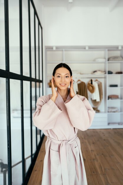 Portrait of a beautiful healthy woman in bathrobe posing at camera indoors