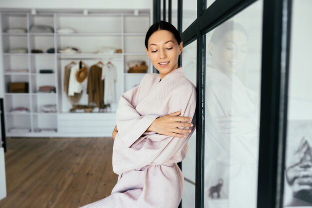 屋内のカメラでポーズをとってバスローブで美しい健康な女性の肖像画