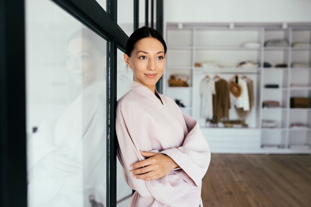 Portrait of a beautiful healthy woman in bathrobe posing at camera indoors