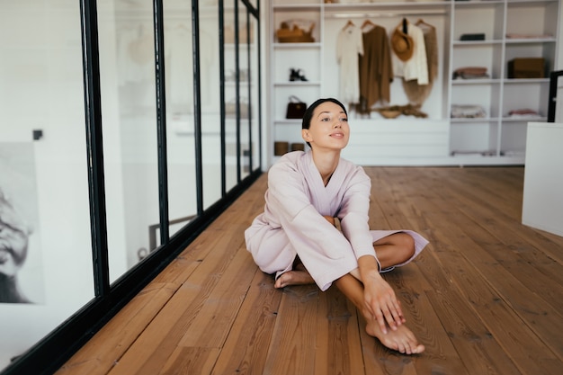 Portrait of a beautiful healthy woman in bathrobe posing at camera indoors