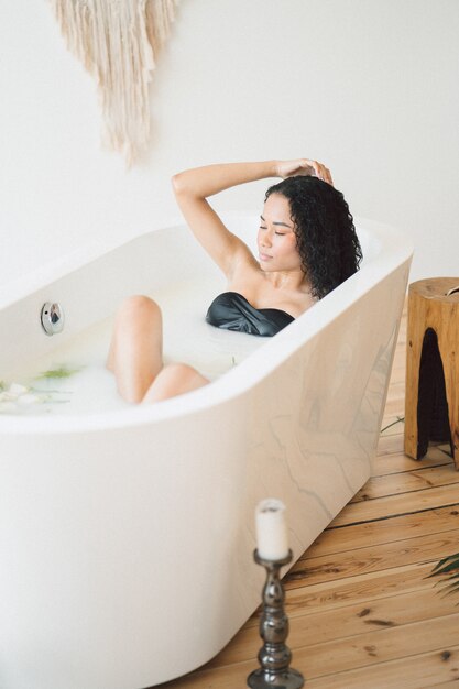 Portrait of beautiful lady at empty room having a milk bath and thinking holding her hair