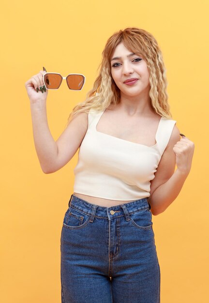Portrait of beautiful lady holding sunglasses and looking at the camera