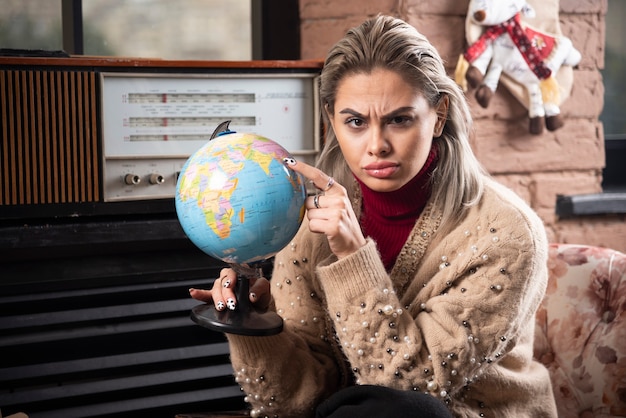 Free photo portrait of beautiful lady pointing at a world globe