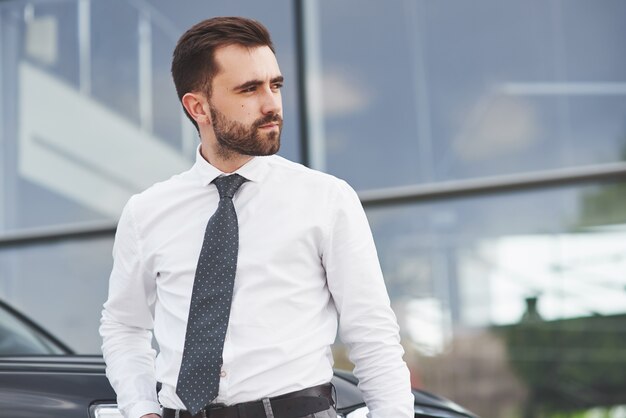 Портрет красивого мужчины в деловой одежде, стоящего снаружи в офисе.