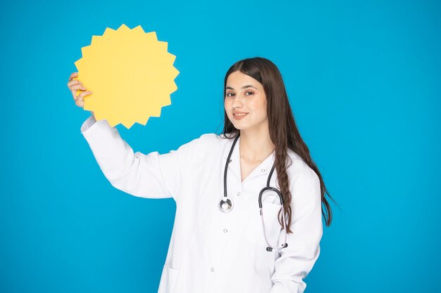 Portrait of beautiful mature woman doctor in lab coat for hospital shooting in studio