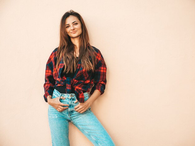 Portrait of beautiful model. Sexy female dressed in summer hipster checkered shirt and jeans. Trendy girl posing near wall in the street