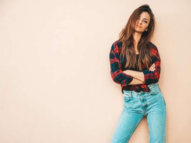 Portrait of beautiful model. Sexy female dressed in summer hipster checkered shirt and jeans. Trendy girl posing near wall in the street