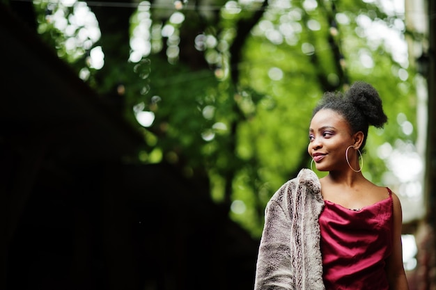 Ritratto di una bella giovane donna africana naturale con capelli afro modello nero in abito di seta rossa