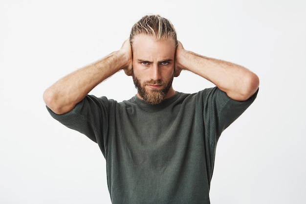 Portrait of beautiful nordic bearded guy closing ears with hands