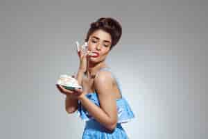 Free photo portrait of beautiful pin-up woman eating cake