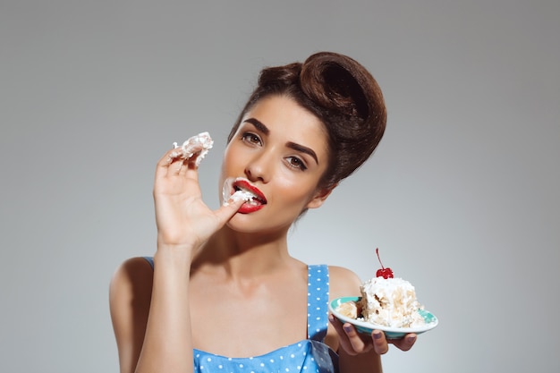 Portrait of beautiful pin-up woman eating cake