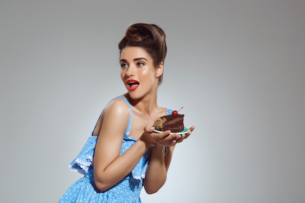 Portrait of beautiful pin-up woman holding cake in hands