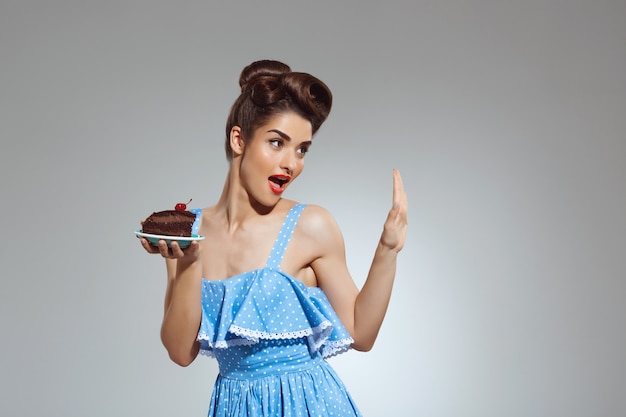 Portrait of beautiful pin-up woman holding cake in hands