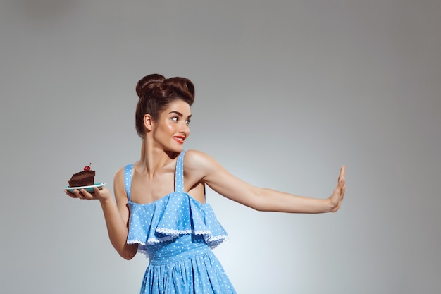 Portrait of beautiful pin-up woman holding cake in hands