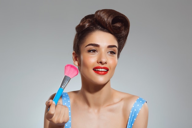 Free photo portrait of beautiful pin-up woman holding make-up brush