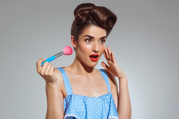 Portrait of beautiful pin-up woman holding make-up brush