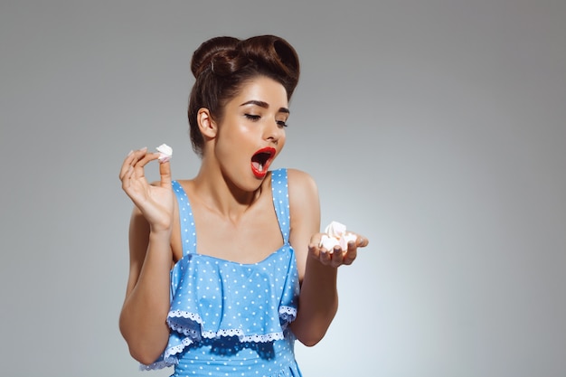 Portrait of beautiful pin-up woman holding sweeties in hands