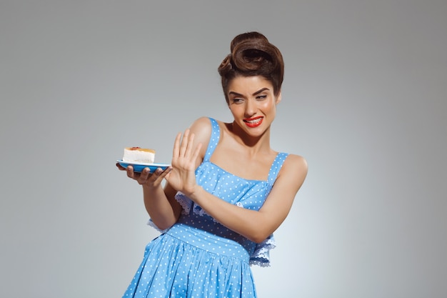 Ritratto di bella donna pin-up che rifiuta di mangiare la torta