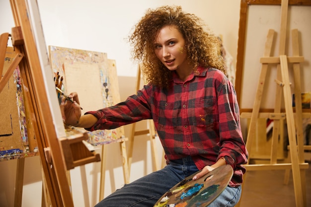 Portrait of beautiful redhead curly artist during her work