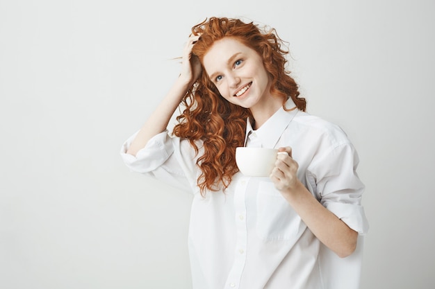 컵을 들고 웃 고 아름 다운 빨간 머리 여자의 초상화입니다.