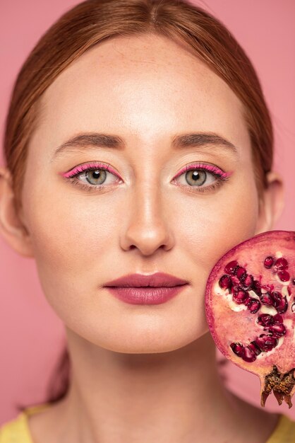 Portrait of beautiful redhead woman holding a fruit