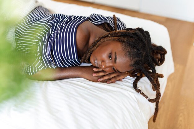 ベッドに横たわっている美しく官能的なアフリカの若い女性の肖像画ベッドに横たわっている美しい女性