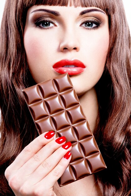 Portrait of beautiful sexy woman with bar of chocolate. Closeup face with bright makeup, isolated on white.