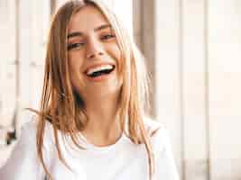 Foto gratuita il ritratto di bello modello biondo sorridente si è vestito in vestiti dei pantaloni a vita bassa dell'estate.