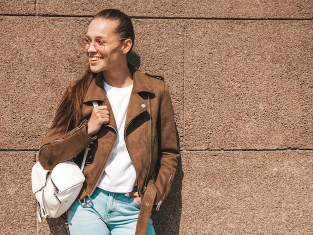 Foto gratuita il ritratto di bello modello castana sorridente si è vestito in vestiti del rivestimento e dei jeans dei pantaloni a vita bassa dell'estate