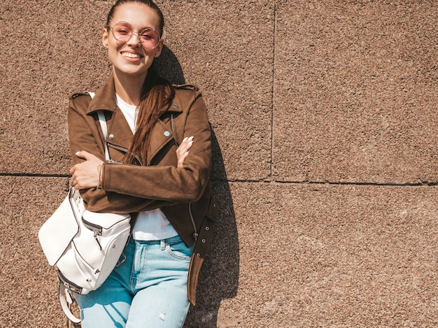 夏の流行に敏感なジャケットとジーンズの服に身を包んだ美しい笑顔ブルネットモデルの肖像