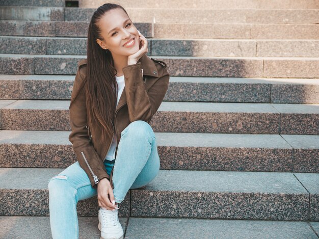 Portrait of beautiful smiling brunette model dressed in summer hipster jacket and jeans clothes. 