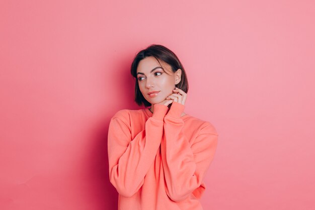 Portrait of beautiful smiling cute brunette woman model in casual peach sweater clothes with bright makeup and pink lips isolated