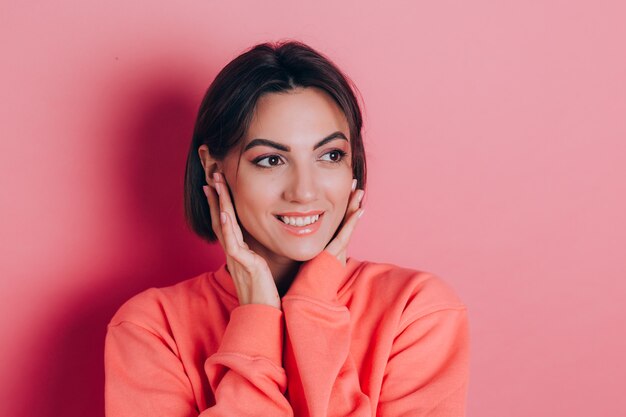 Portrait of beautiful smiling cute brunette woman model in casual peach sweater clothes with bright makeup and pink lips isolated