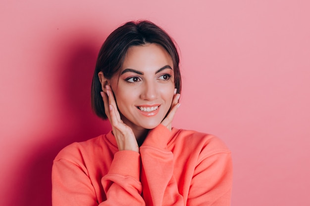 Портрет красивой улыбающейся милой брюнетки модели в повседневной персиковой одежде свитера с ярким макияжем и розовыми губами изолированы