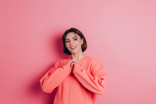 Portrait of beautiful smiling cute brunette woman model in casual peach sweater clothes with bright makeup and pink lips isolated