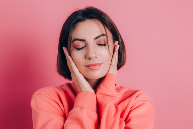 Portrait of beautiful smiling cute brunette woman model in casual peach sweater clothes with bright makeup and pink lips isolated