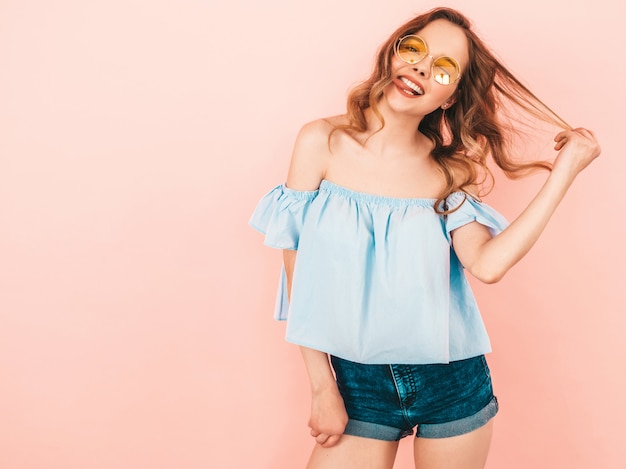 Portrait of beautiful smiling cute model in round sunglasses. Girl in summer colorful clothes. Model posing