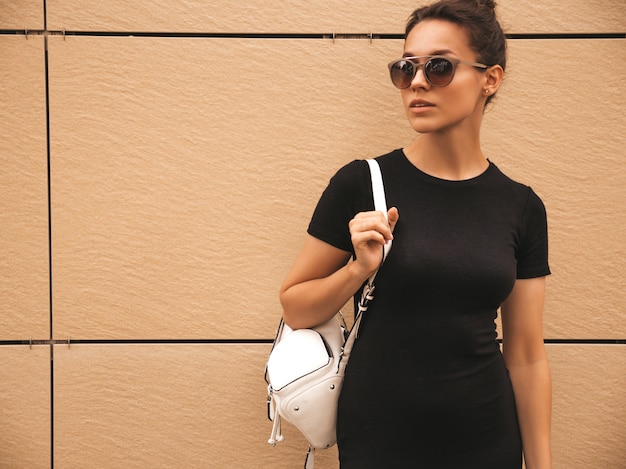 Portrait of beautiful smiling model dressed in summer clothes. Trendy girl posing in the street. Funny and positive woman having fun in sunglasses