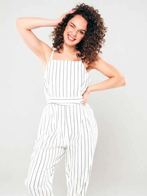 Portrait of beautiful smiling model with afro curls hairstyle dressed in summer hipster clothes.Sexy carefree girl posing in studio on gray background.Trendy funny and positive woman