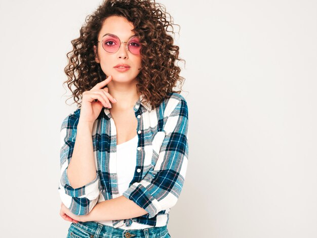 Portrait of beautiful smiling model with afro curls hairstyle dressed in summer hipster clothes.Sexy carefree girl posing in studio on gray background.Trendy funny and positive woman