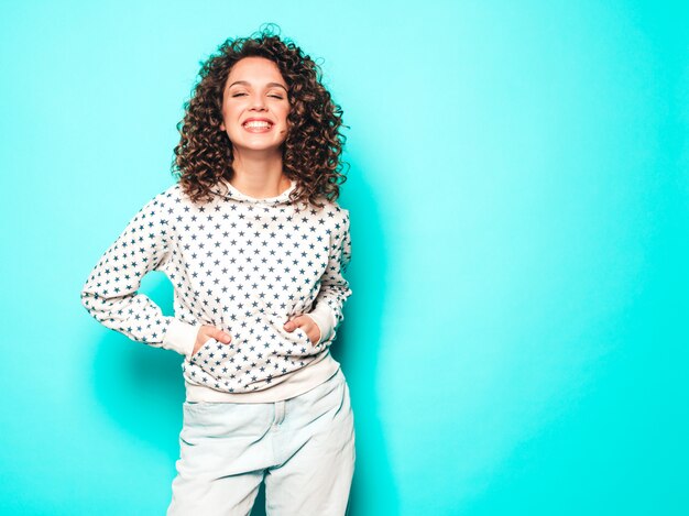 Portrait of beautiful smiling model with afro curls hairstyle dressed in summer hipster clothes.Trendy funny and positive woman in white hoodie