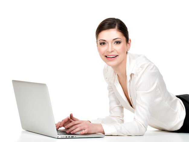 Portrait of a  beautiful smiling woman with laptop in white shirt lying on floor - isolated on white. 
