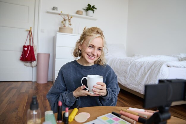 Portrait of beautiful social media beauty blogger sitting in front of digital camera on floor in