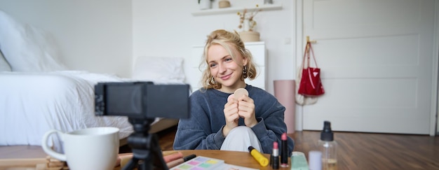 Portrait of beautiful and stylish young woman vlogger recording video on her digital camera in a