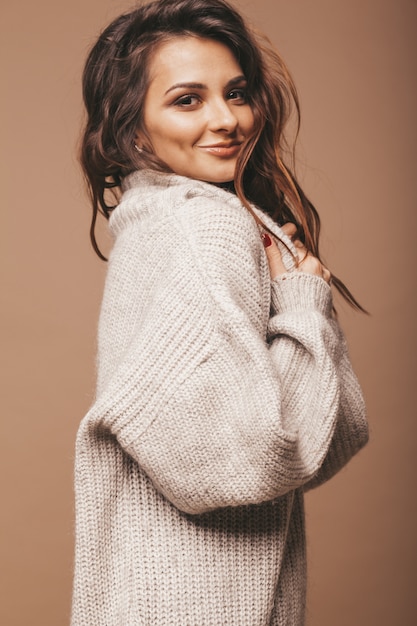 portrait of beautiful sweet cute smiling brunette woman. Girl in casual gray sweater. Model posing in studio