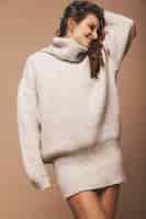 Foto gratuita ritratto di bella dolce carina donna bruna sorridente. ragazza in maglione casual grigio. modello in posa in studio