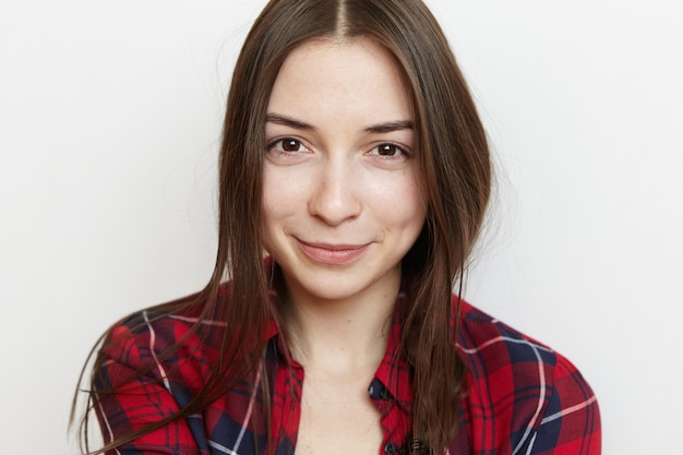 Foto gratuita ritratto di una bella ragazza adolescente con i capelli disordinati e un sorriso carino che indossa la camicia a scacchi rossa